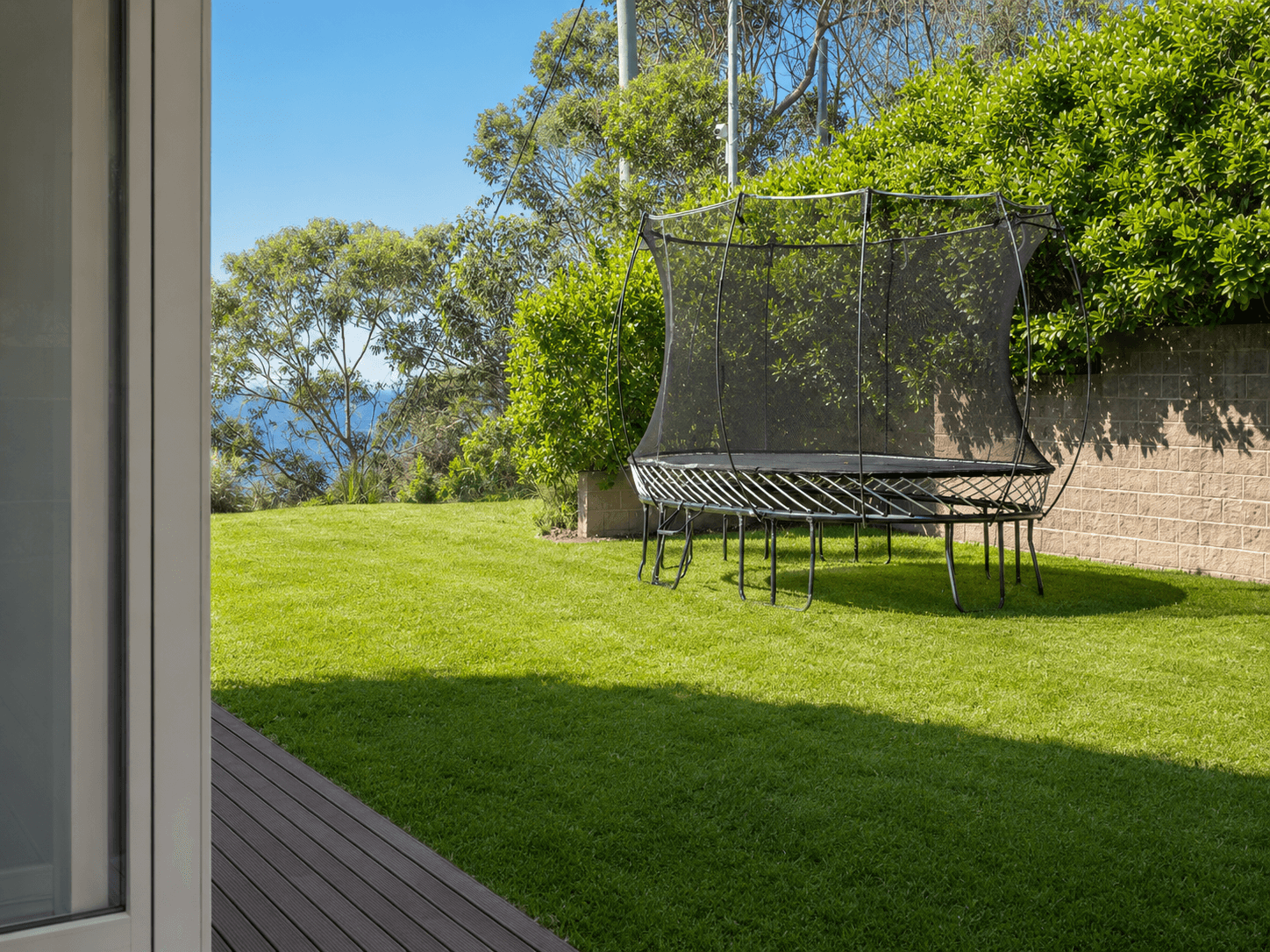 Sunny coastal backyard with trampoline